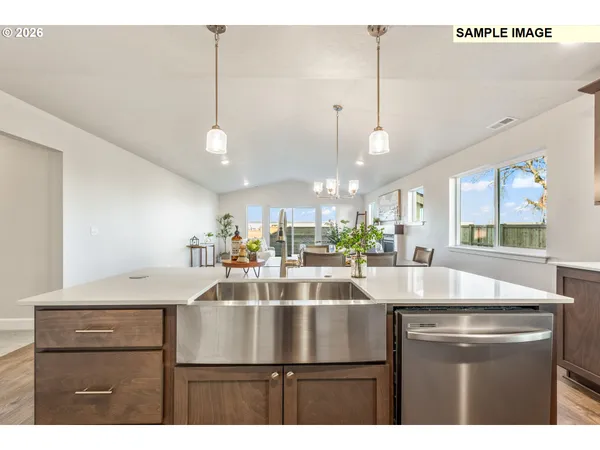 a kitchen with a sink a counter top space and living room view