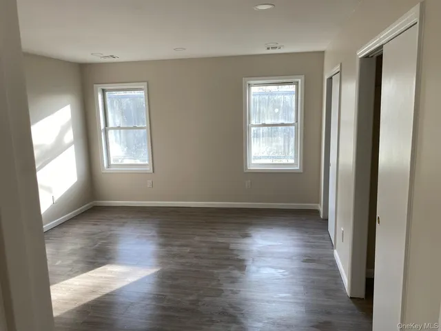a view of an empty room with wooden floor and window