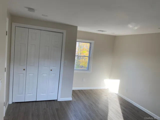 a view of an empty room with wooden floor and closet
