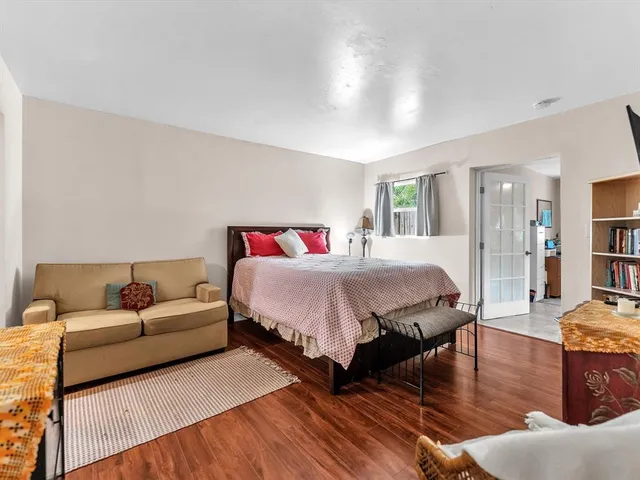 a spacious bedroom with a bed a couch and a potted plant on the dresser