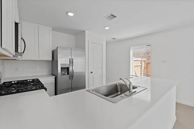 a kitchen with stainless steel appliances granite countertop a refrigerator a stove and a sink with wooden floor