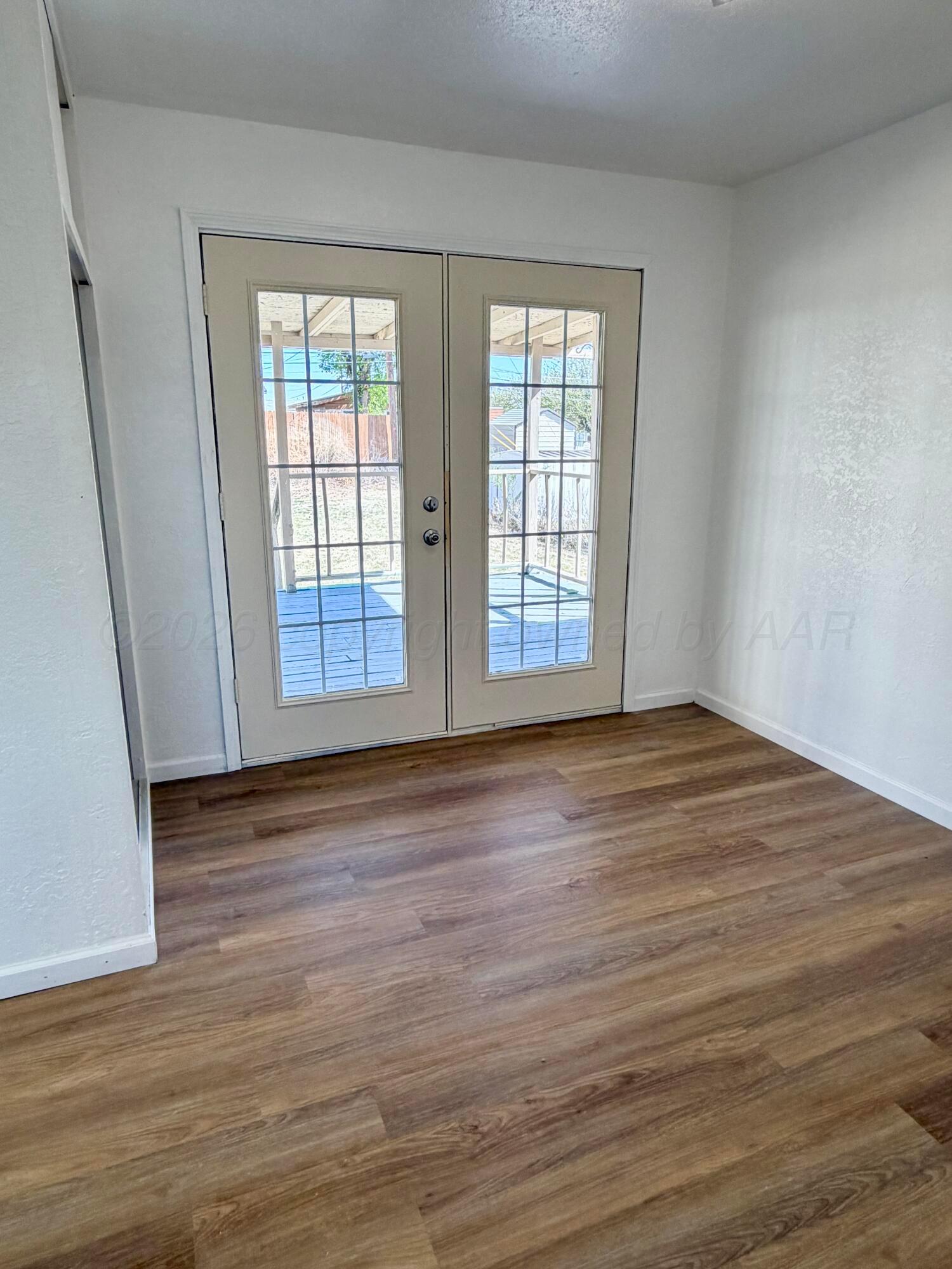 104 Warwick Street Borger, TX 79007 - Photo 16 of 28 an empty room with wooden floor and windows