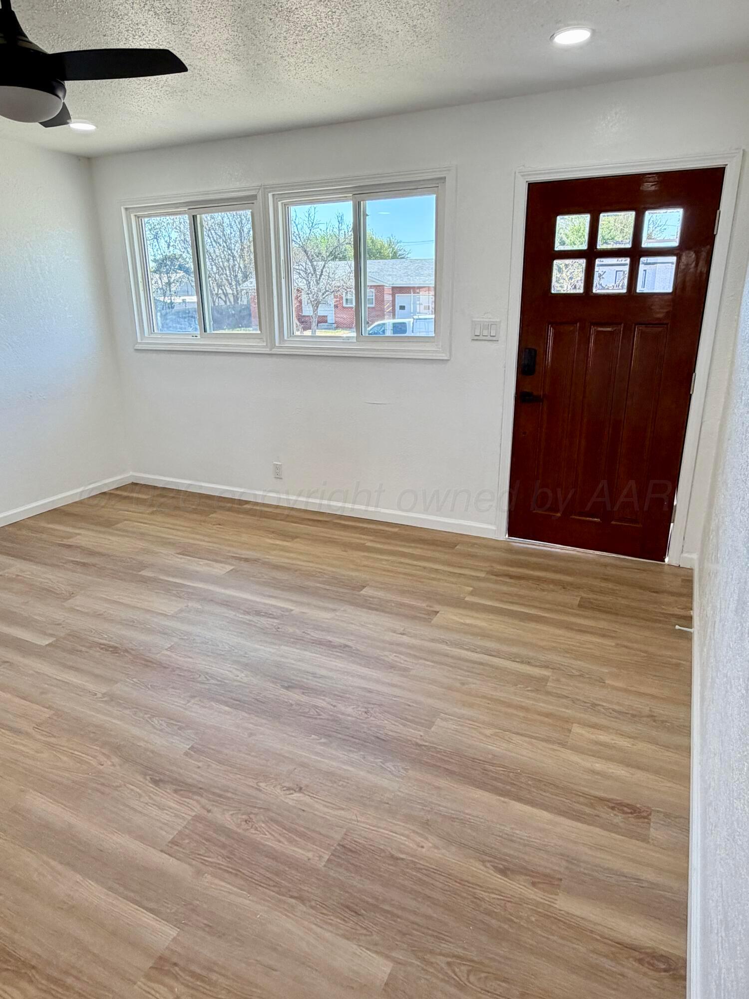 104 Warwick Street Borger, TX 79007 - Photo 8 of 28 a view of an empty room with wooden floor and a window