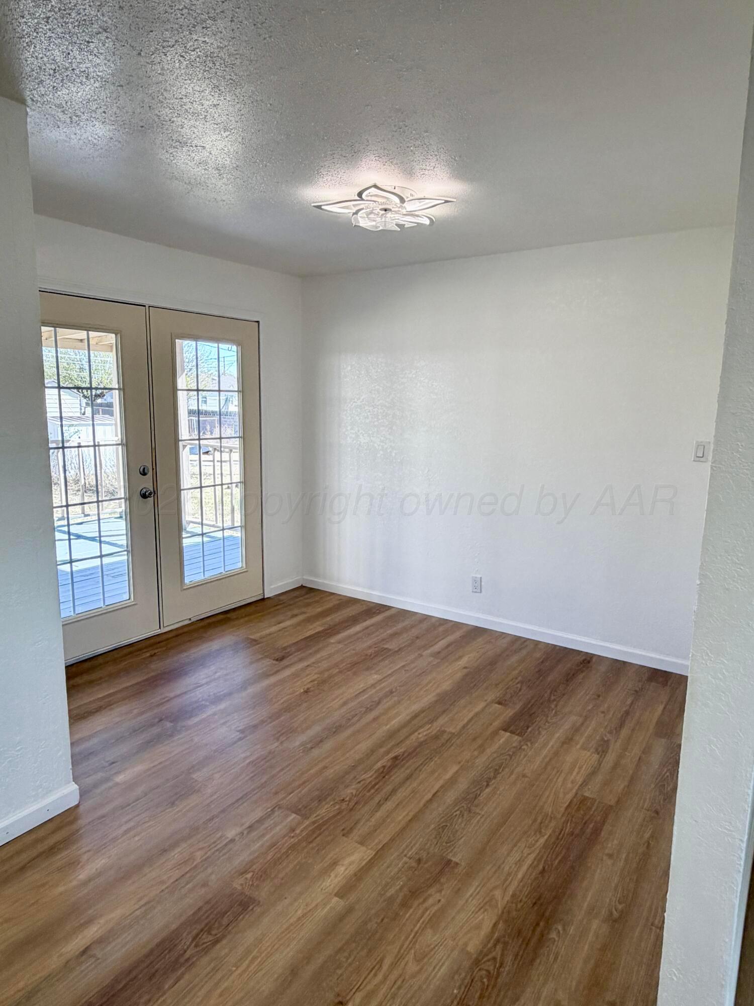 104 Warwick Street Borger, TX 79007 - Photo 9 of 28 a view of an empty room with wooden floor and a window