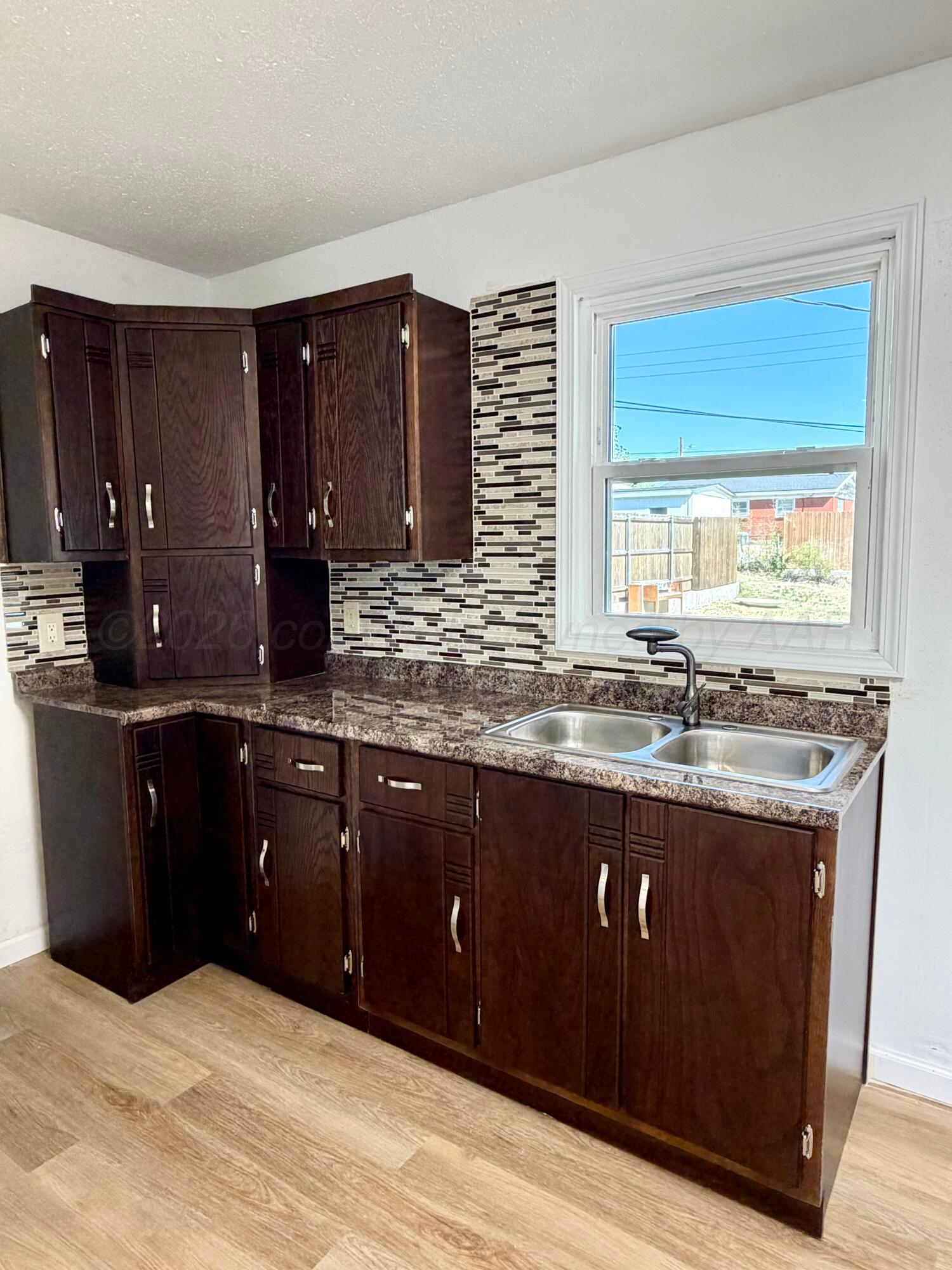 104 Warwick Street Borger, TX 79007 - Photo 10 of 28 a kitchen with granite countertop a sink cabinets and wooden floor