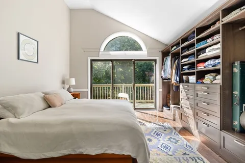 a bedroom with a bed a dresser and a large window