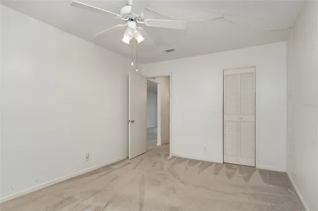 an empty room with a ceiling fan and a window