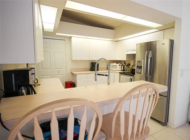 a kitchen with stainless steel appliances kitchen island granite countertop a refrigerator a stove and white cabinets with wooden floor