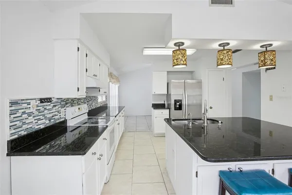 a large kitchen with a stove a white cabinet and a granite countertops with wooden floor