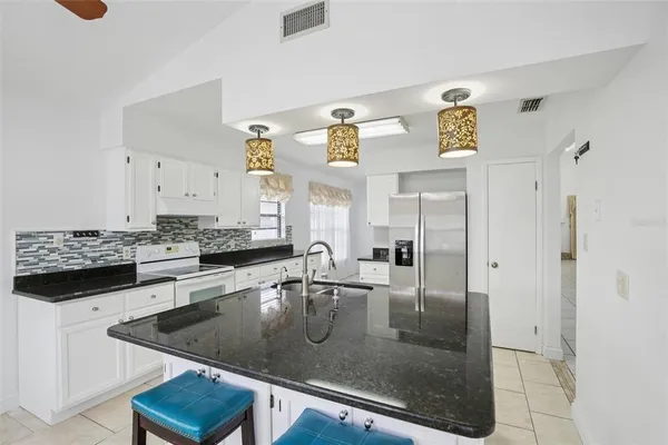 a kitchen with stainless steel appliances granite countertop a sink a stove and a refrigerator