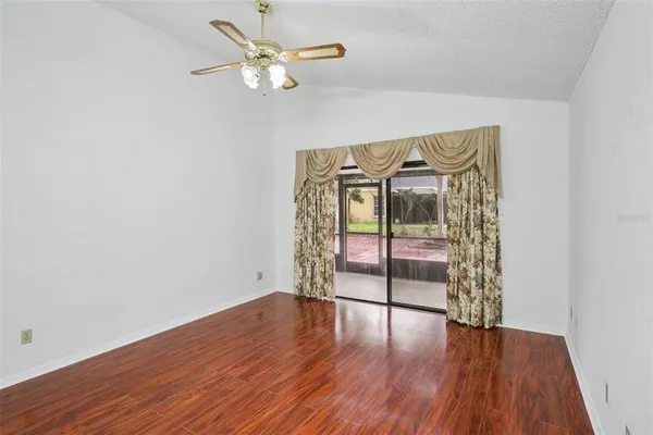 an empty room with wooden floor fan and windows