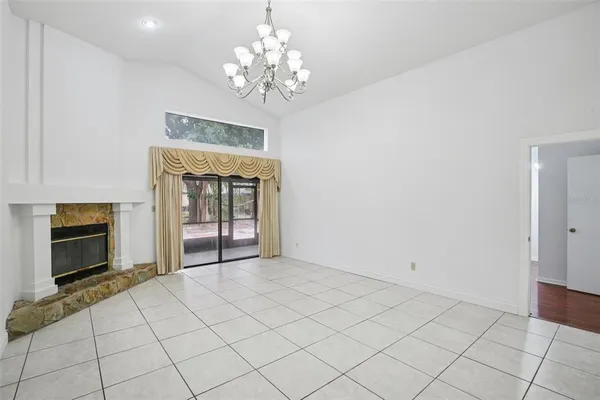 a view of an empty room with a fireplace and a chandelier