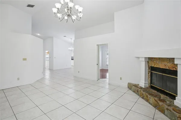 an empty room with chandelier and fireplace