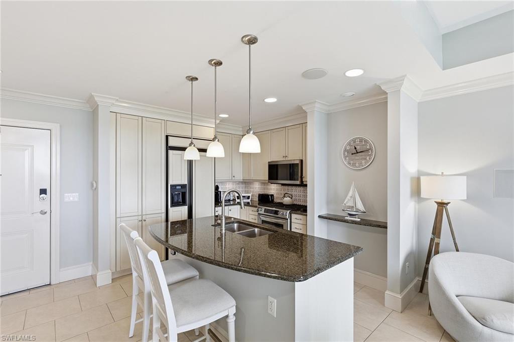9123 Strada Place, Unit 7409 Naples, FL 34108 - Photo 5 of 34 a kitchen with kitchen island a sink stove and refrigerator