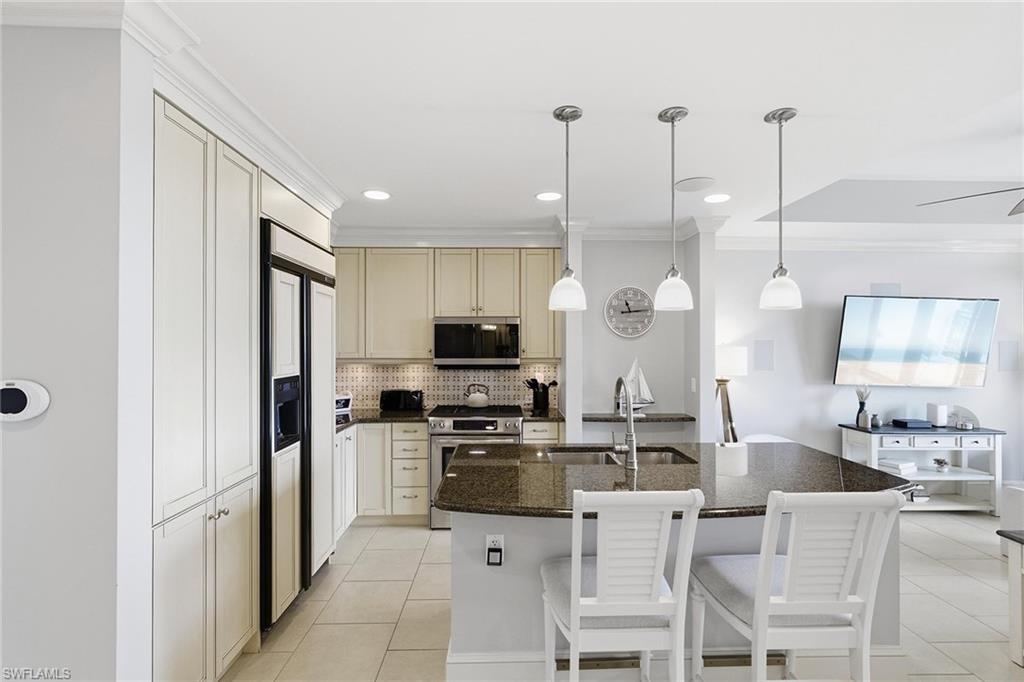 9123 Strada Place, Unit 7409 Naples, FL 34108 - Photo 6 of 34 a kitchen with stainless steel appliances kitchen island granite countertop a stove a sink a refrigerator a dining table and chairs