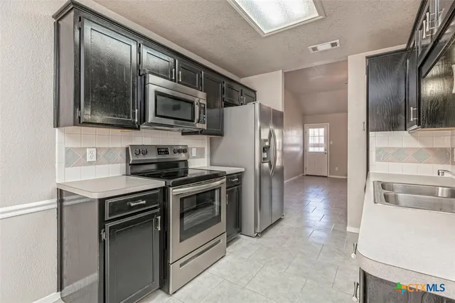 a kitchen with stainless steel appliances granite countertop a stove microwave and refrigerator