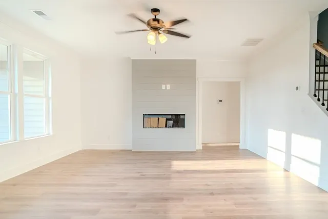 a view of a big room with wooden floor and a chandelier fan