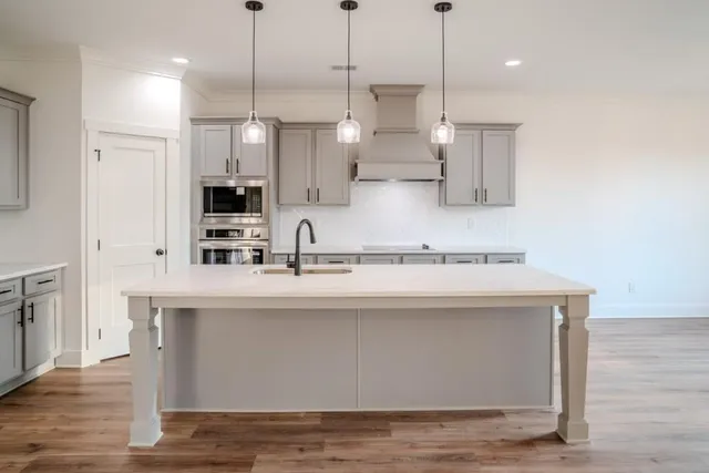 a view of a kitchen with kitchen island a sink stainless steel appliances and cabinets