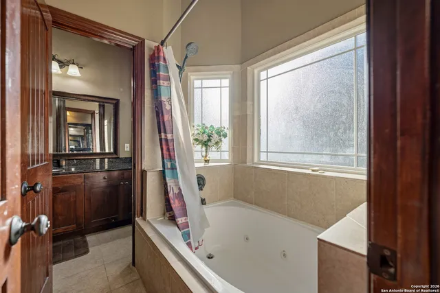 a bathroom with a tub a sink and a large mirror