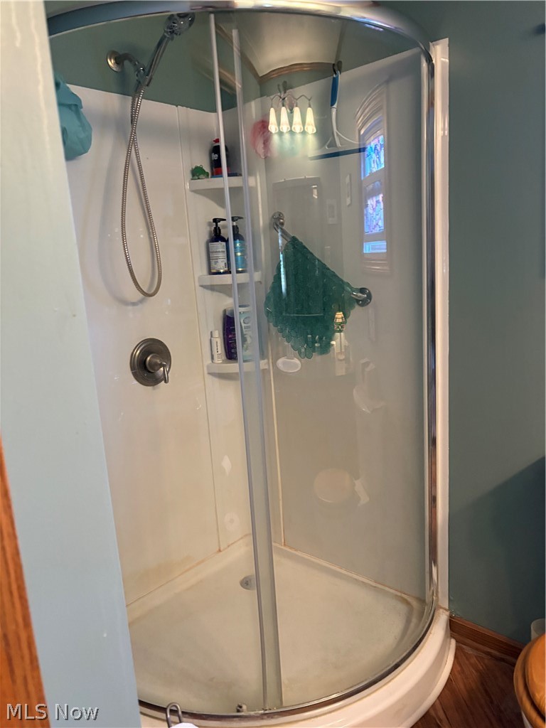 8701 Mayfield Road, Unit 148 Chesterland, OH 44026 - Photo 12 of 24 Corner shower enclosure with curved glass door, integrated shelving, handheld shower fixture, and a built-in shower base