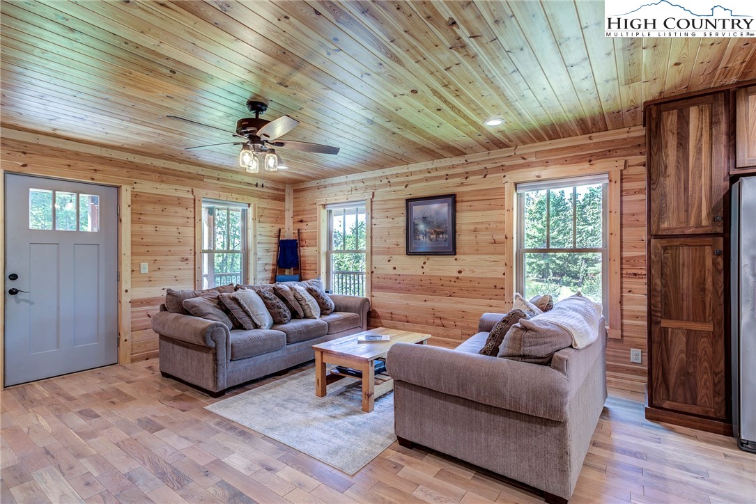 1210 Staghorn Road Purlear, NC 28665 - Photo 17 of 42 a living room with furniture a ceiling fan a flat screen tv and a large window