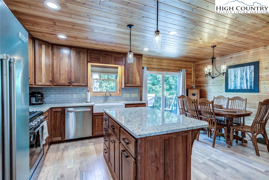 1210 Staghorn Road Purlear, NC 28665 - Photo 19 of 42 a kitchen with granite countertop a stove a sink dishwasher a dining table and chairs with wooden floor