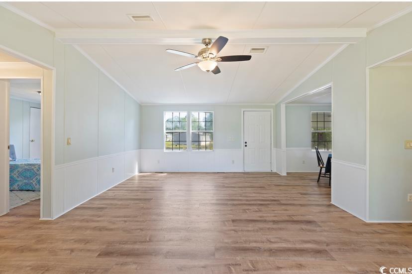 1030 Levi Street Manning, SC 29102 - Photo 11 of 31 Unfurnished living room with a ceiling fan, a decorative wall, ornamental molding, wood finished floors, and a wainscoted wall