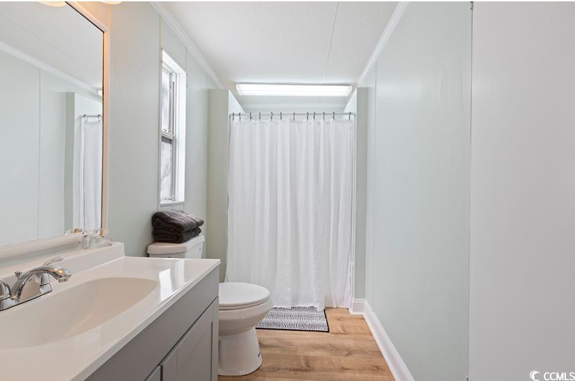 1030 Levi Street Manning, SC 29102 - Photo 23 of 31 Bathroom featuring toilet, vanity, wood finished floors, crown molding, and curtained shower