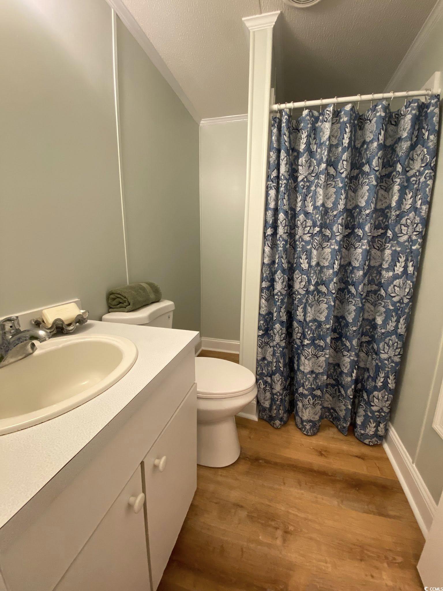 1030 Levi Street Manning, SC 29102 - Photo 26 of 31 Full bath with ornamental molding, wood finished floors, vanity, toilet, and curtained shower