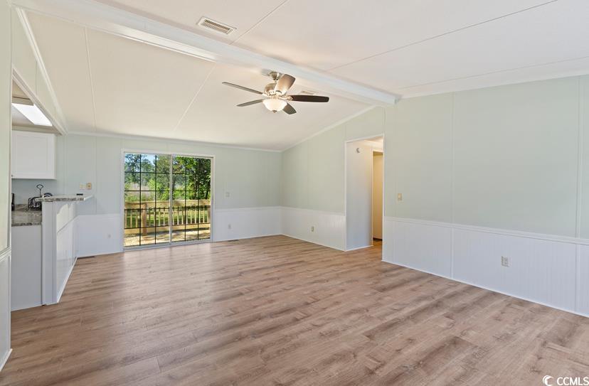 1030 Levi Street Manning, SC 29102 - Photo 7 of 31 Unfurnished living room featuring a ceiling fan, light wood-type flooring, wainscoting, and a decorative wall