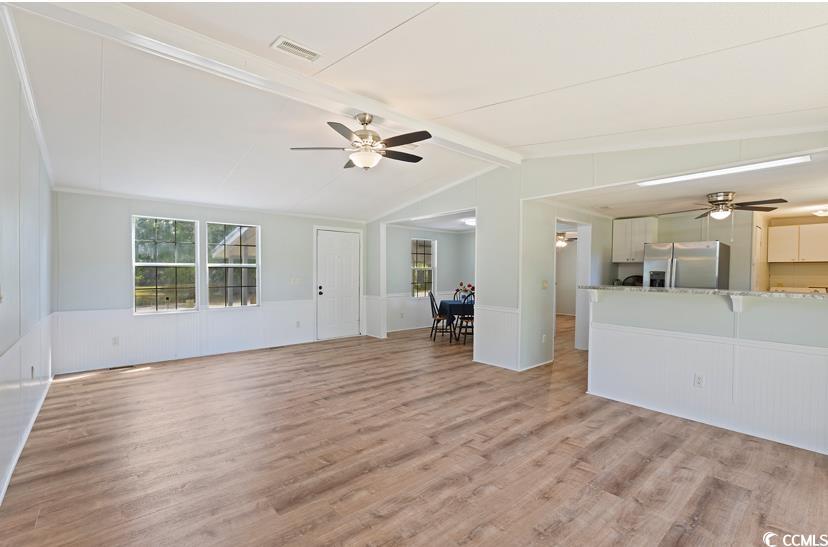 1030 Levi Street Manning, SC 29102 - Photo 10 of 31 Unfurnished living room featuring a ceiling fan, light wood finished floors, a wainscoted wall, and a decorative wall