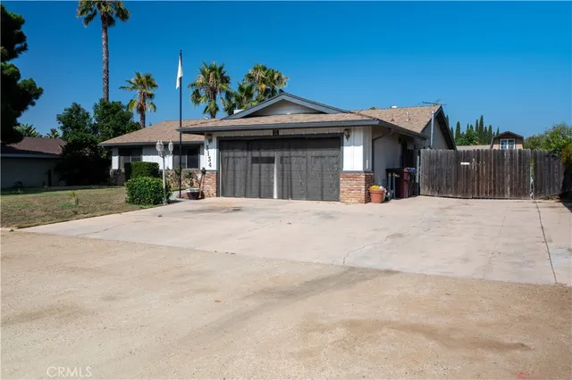 a view of a house with a yard and palm trees