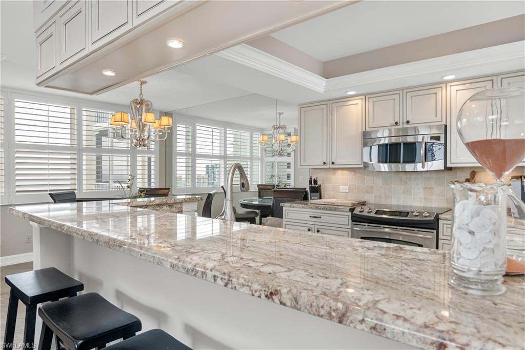 5550 Heron Point Drive, Unit 1804 Naples, FL 34108 - Photo 5 of 20 an open kitchen with granite countertop a stove and a sink