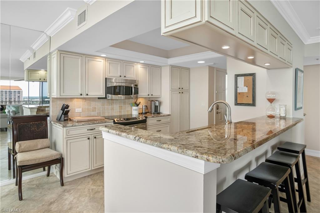 5550 Heron Point Drive, Unit 1804 Naples, FL 34108 - Photo 6 of 20 a kitchen with kitchen island granite countertop a stove a sink and a refrigerator