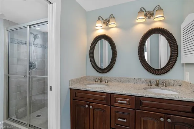 a bathroom with a granite countertop double vanity sink and a mirror