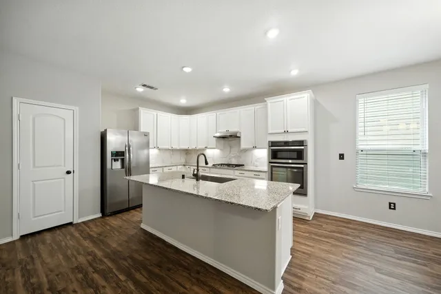 a kitchen with stainless steel appliances granite countertop a refrigerator and a stove top oven