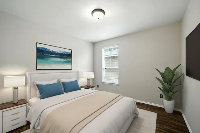 a bedroom with bed plant and window