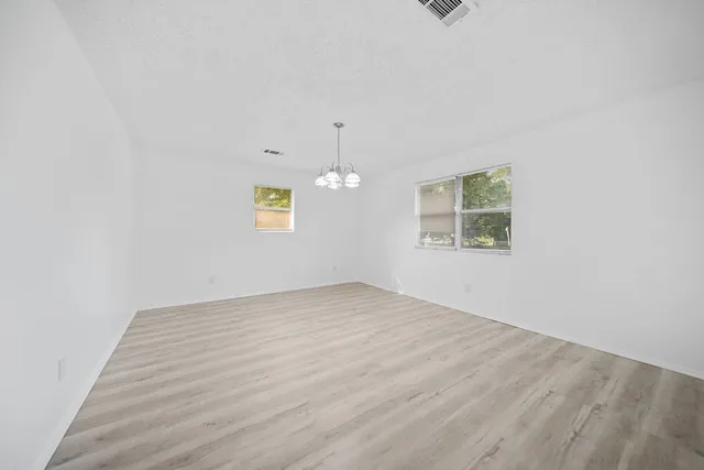 an empty room with wooden floor and chandelier