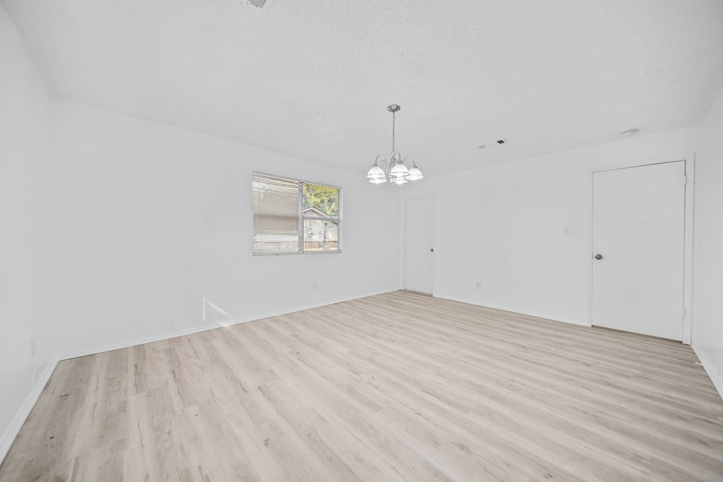 3058 Old Colony Road Huntsville, TX 77320 - Photo 14 of 25 an empty room with wooden floor and chandelier