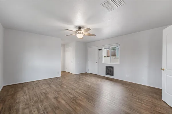 an empty room with wooden floor and windows