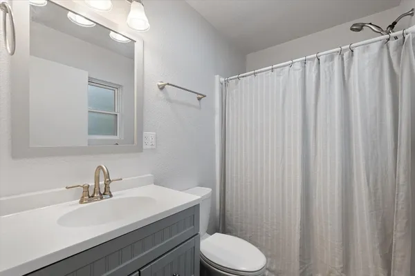 a bathroom with a sink a toilet a mirror and shower curtain
