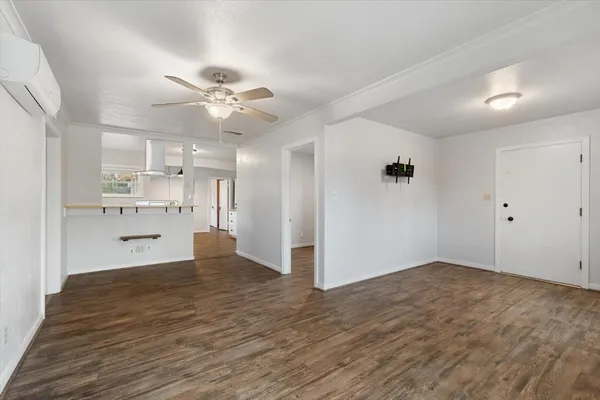 a view of kitchen and empty room with wooden floor