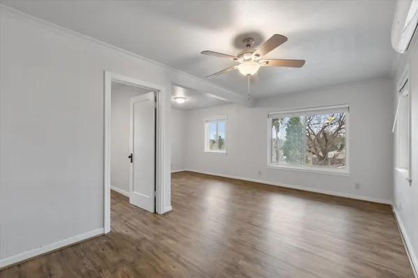 a view of an empty room with wooden floor and a window