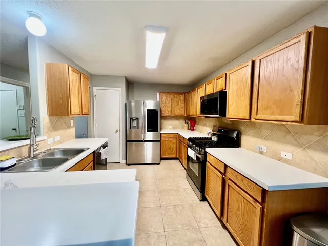 a kitchen with stainless steel appliances granite countertop a sink stove refrigerator and a large window