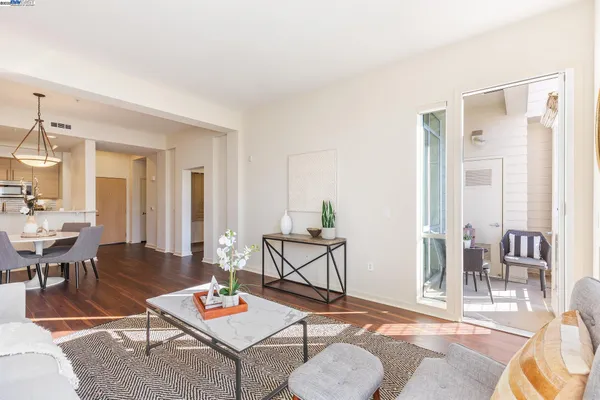 a living room with furniture and a dining table with wooden floor