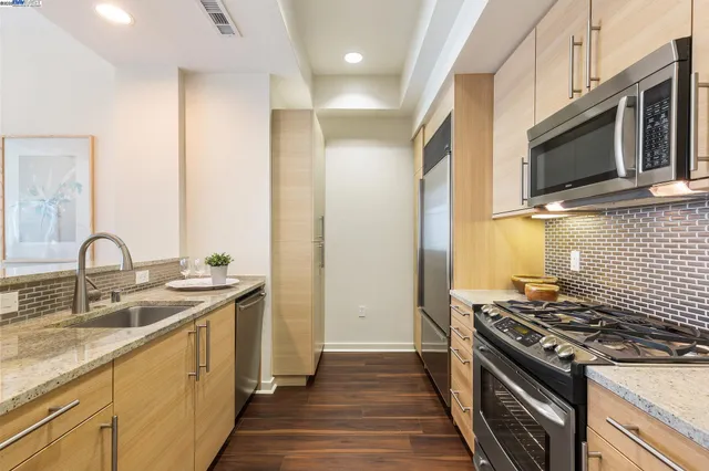 a kitchen with stainless steel appliances granite countertop a stove a sink and a microwave