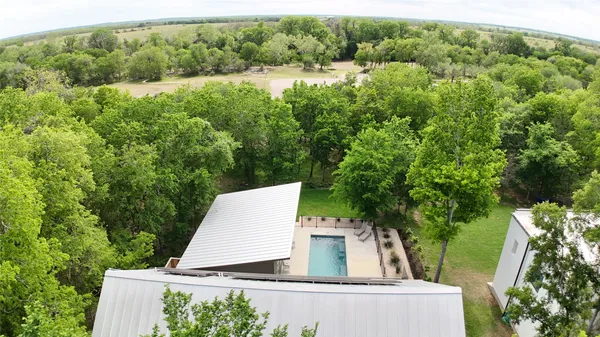 an aerial view of a house with outdoor space and trees all around