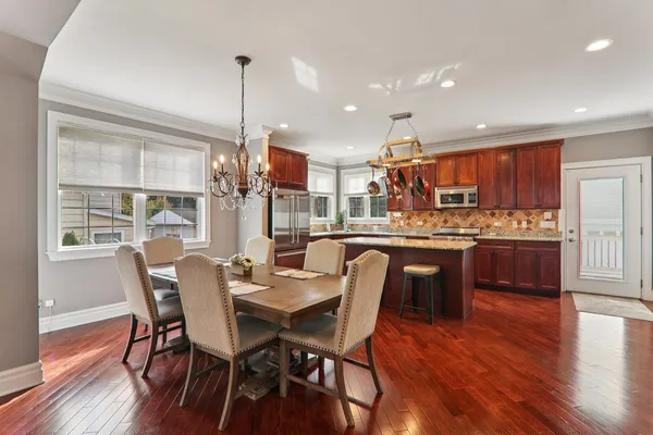a dining room with stainless steel appliances kitchen island granite countertop a dining table chairs and granite counter tops