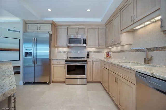 a kitchen with stainless steel appliances granite countertop a refrigerator and a sink