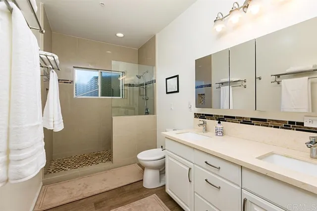 a bathroom with a double vanity sink mirror double shower and a toilet
